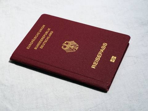 Ein burgunderroter deutscher Reisepass mit goldenen Buchstaben und dem Bundesadler liegt auf einer hellen Oberfläche.